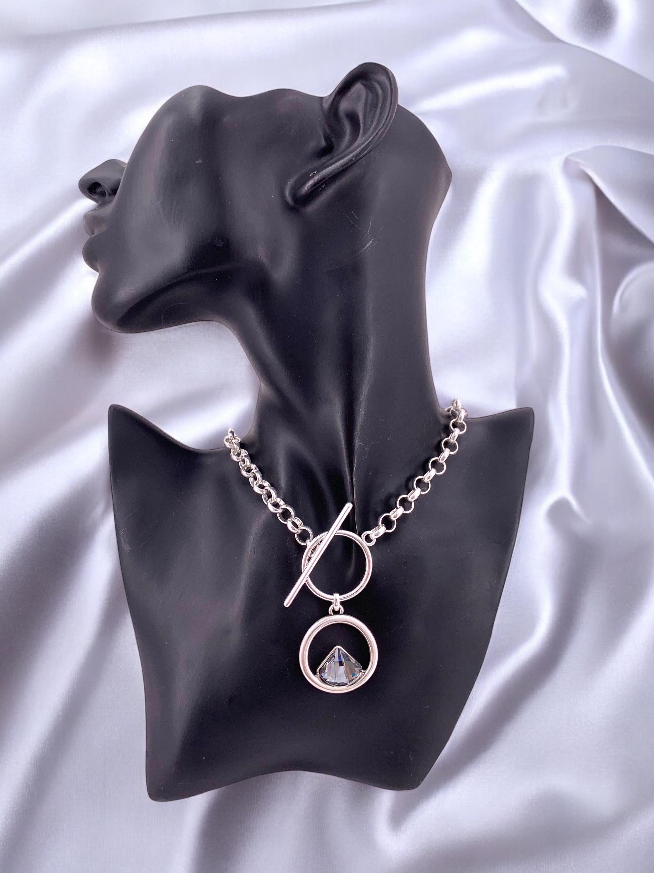 Elegant silver-plated necklace featuring a double-circle pendant with a brilliant triangular Swarovski crystal, finished with toggle clasp