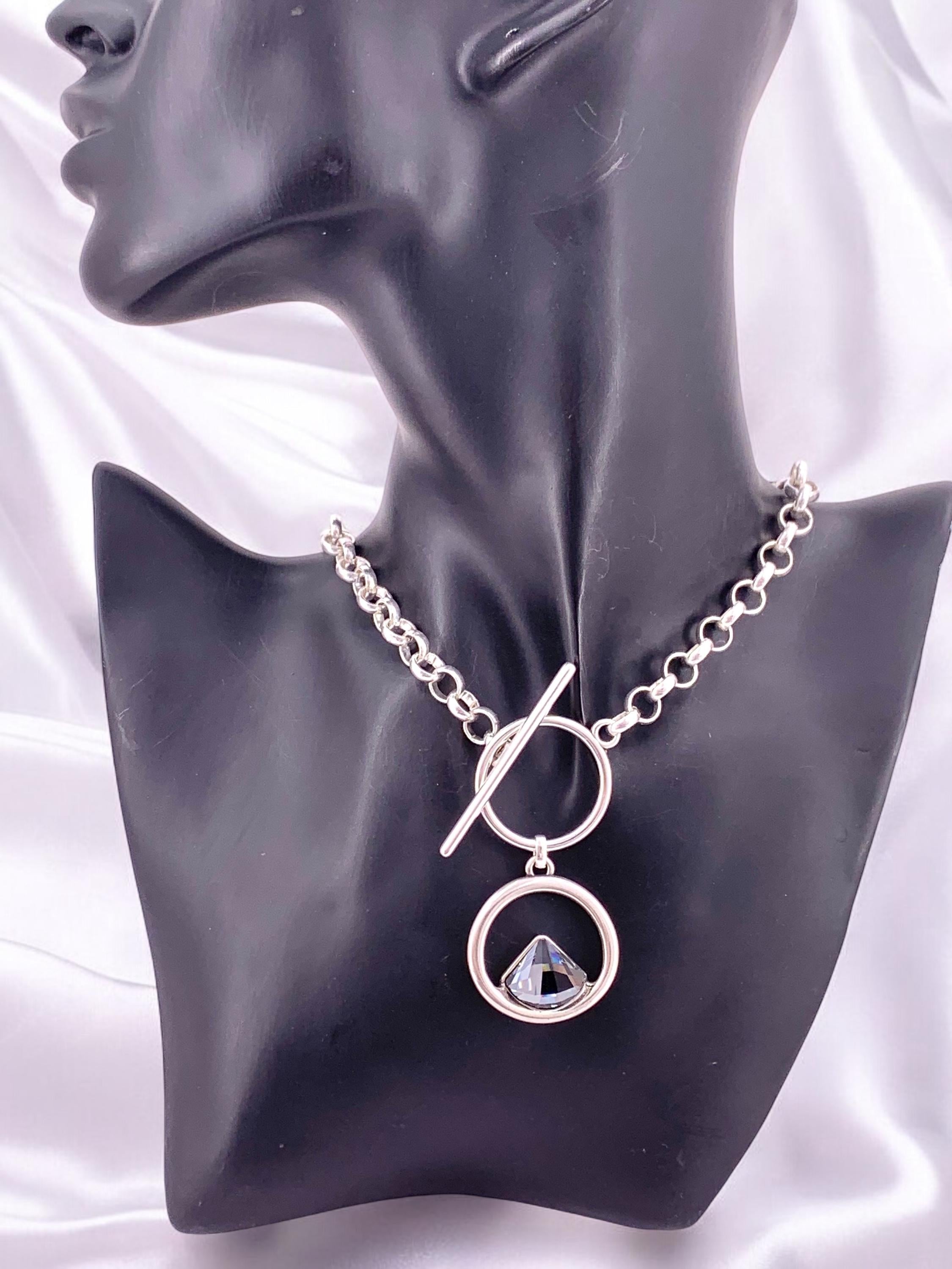 Elegant silver-plated necklace featuring a double-circle pendant with a brilliant triangular Swarovski crystal, finished with toggle clasp