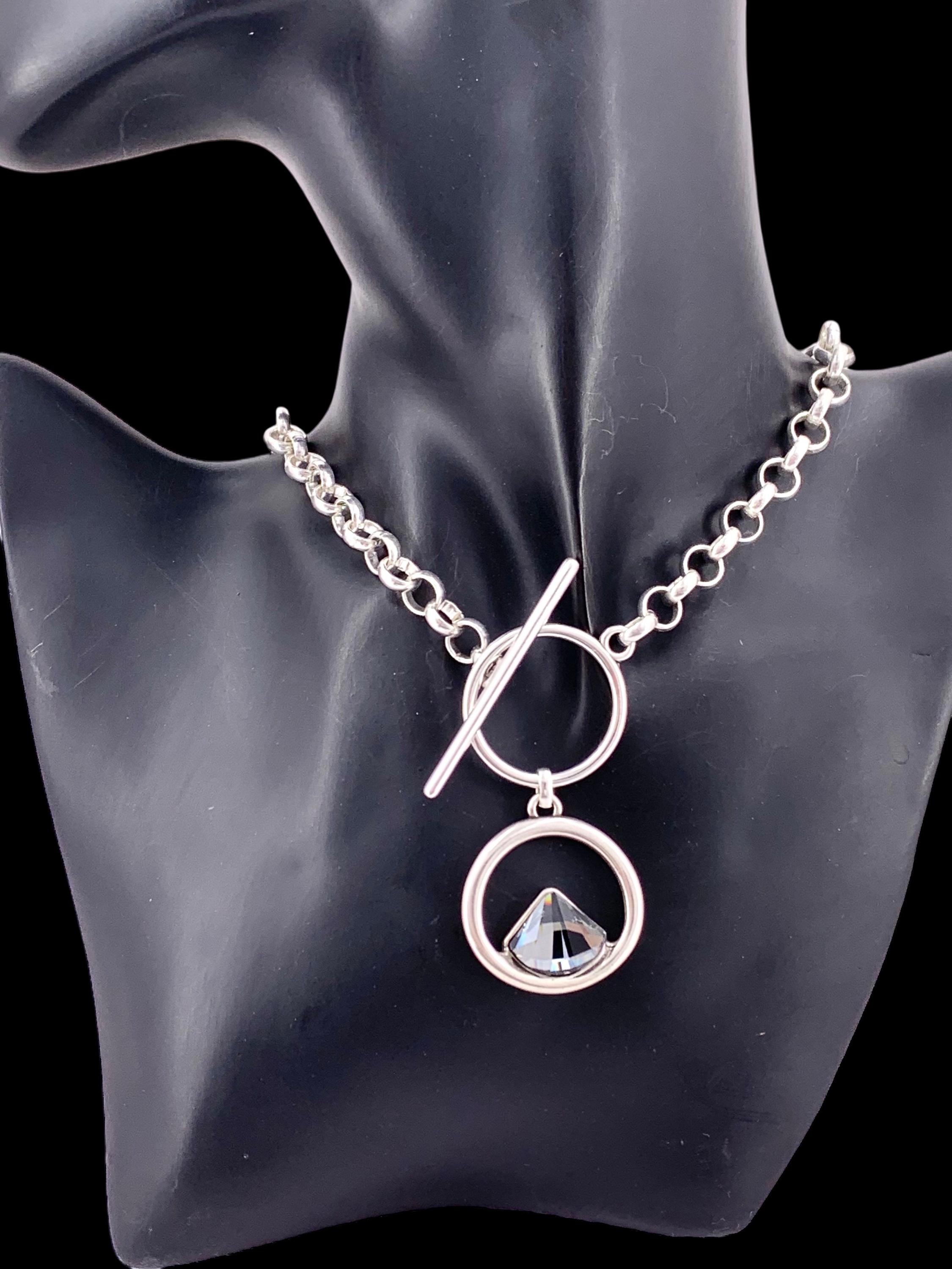 Elegant silver-plated necklace featuring a double-circle pendant with a brilliant triangular Swarovski crystal, finished with toggle clasp